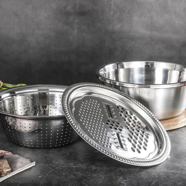 Stainless steel grating basin and bowl set on a dark surface with a blurred background