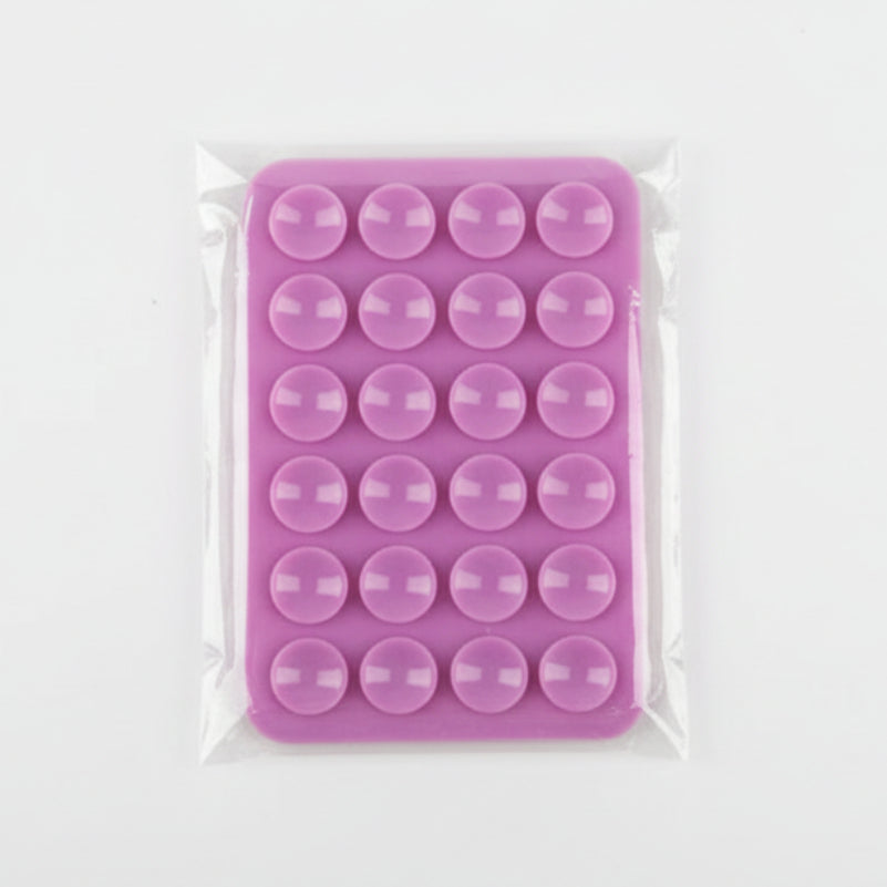 Pink silicone phone mount with circular cavities in clear plastic packaging on a gray background