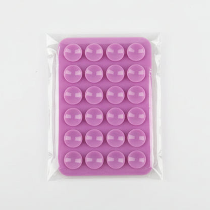 Pink silicone phone mount with circular cavities in clear plastic packaging on a gray background