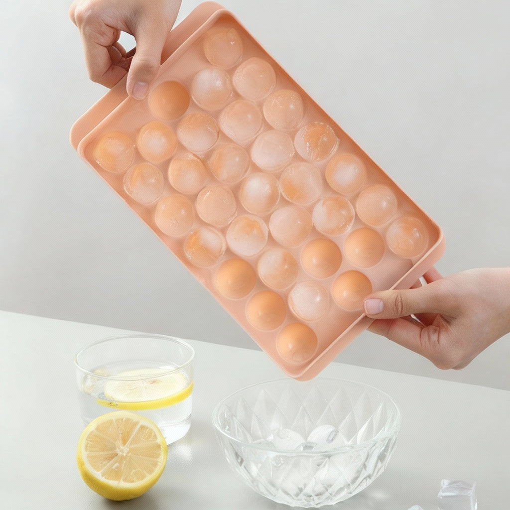 Pink silicone ice cube tray with round compartments, held by hands on a light gray background.