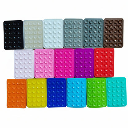 Assorted colorful silicone phone suction mounts on a white background