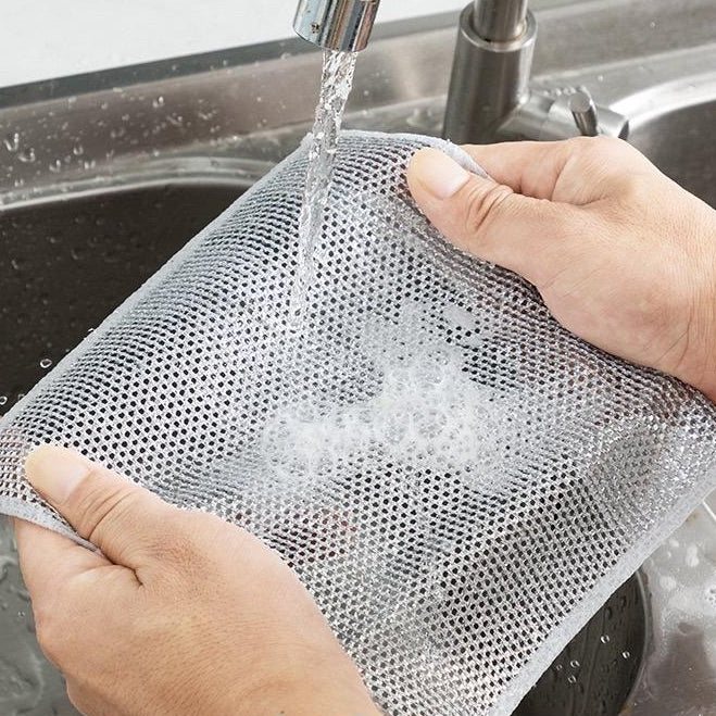 Person washing a Non-scratch Dishwashing Cloth under running water in a sink with text on the screen.