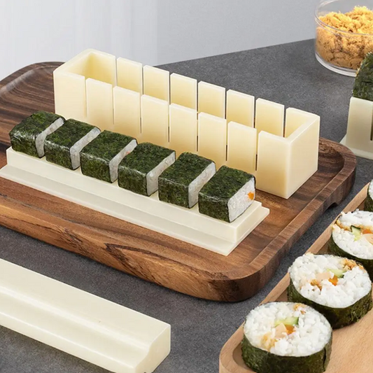 Sushi-making kit with rice blocks, nori sheets, and sushi rolls on a wooden board.
